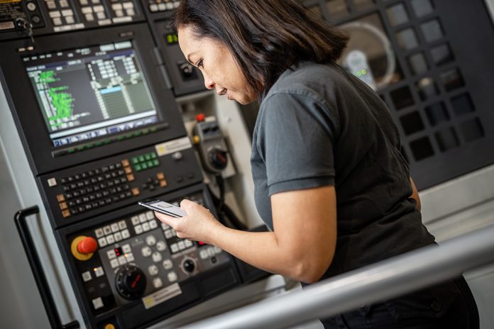 Woman by a machine with a smartphone